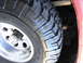 1978 Ford Bronco - A close-up view of a off-road tire and wheel assembly, showing detailed tread pattern and suspension parts.