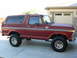 1978 Ford Bronco - Side view of a red 1978 Ford Bronco, identified by its badge, parked on a paved driveway.