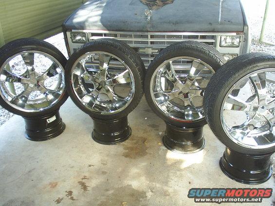four chrome rims and tires in front of a truck