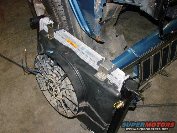 Radiator and fan assembly with blue body panel and tire visible