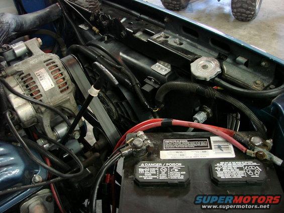 Engine bay showing alternator, battery, and hoses