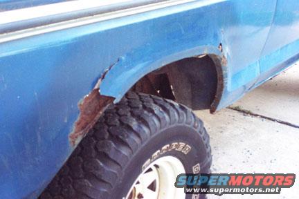 Blue SUV rear fender with significant rust damage around the wheel well. Off-road tire visible