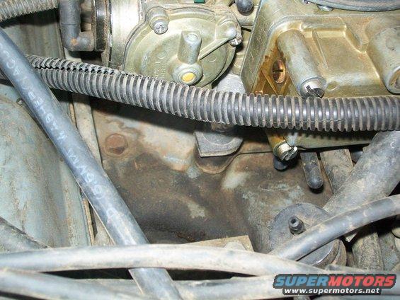 Close-up of a vehicle's engine carburetor and hoses. Text on a hose reads "6.5MM WASHER AC"