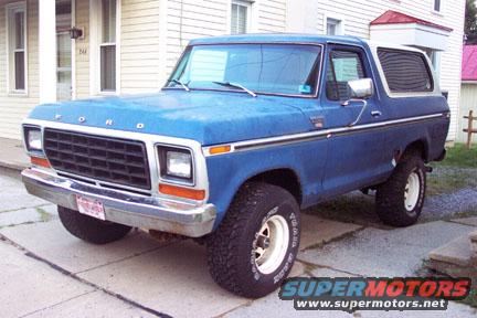 Blue Ford Bronco parked on a sidewalk. The grille and headlights suggest it's a 1978 model