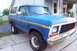 1979 Ford Bronco - A blue Ford Bronco with a white top is parked on a concrete driveway in front of a house.