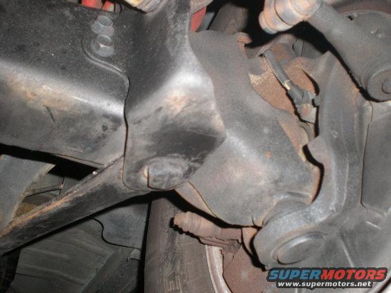 Close-up of rusty vehicle suspension parts, including a control arm and brake caliper assembly
