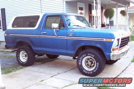 Blue Ford Bronco parked on driveway. White roof, chrome trim, white wheels