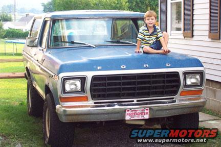 Blue 1978 Ford Bronco with a boy sitting on the hood