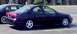 1999 Ford Taurus - A dark 1999 Ford Taurus sedan is seen from the side, parked next to another vehicle.