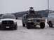 1981 Ford Bronco - A Humvee carrying a snowmobile is parked in a snowy area next to other vehicles.