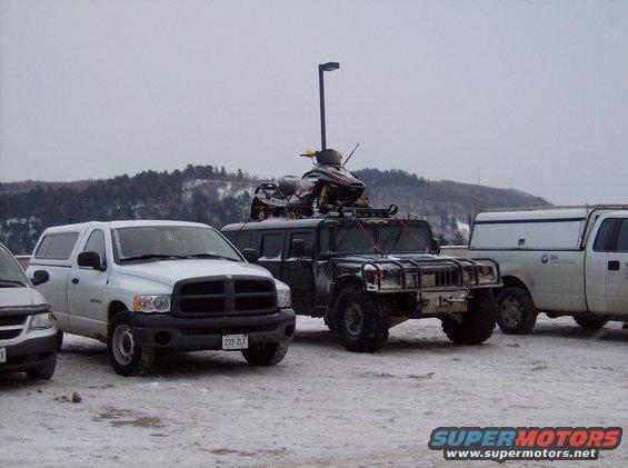 Humvee with snowmobile on roof, parked in snow