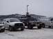 1981 Ford Bronco - A Humvee is parked in the snow with a snowmobile loaded onto its roof rack, alongside other vehicles.