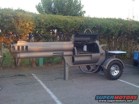 Barbecue grill shaped like a revolver, with '500 S&W MAGNUM' text on the barrel