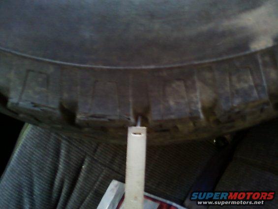 Measuring tire tread depth with a ruler inside a vehicle