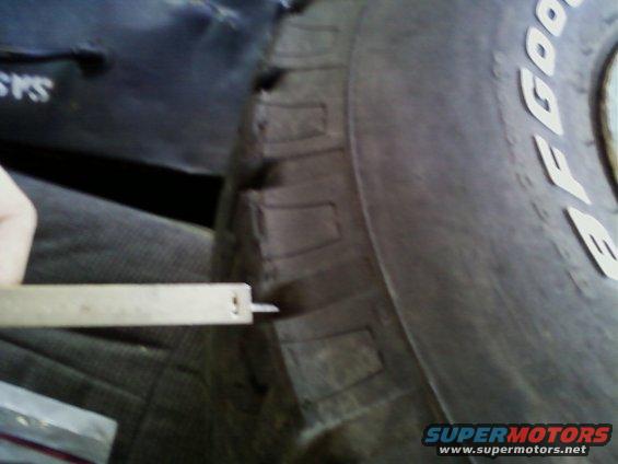 Tire tread being measured with a caliper. "Supermotors" logo visible