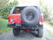 1989 Ford Bronco - The rear of a red SUV is shown, a spare tire, a custom bumper, and a license plate.