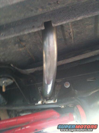 underneath shot of a shiny exhaust pipe attached to a vehicle frame