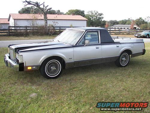 Silver and black 1984 Lincoln Continental Mark VII pickup conversion with a black vinyl roof and wire wheels, parked on grass