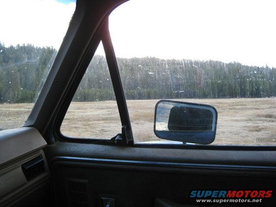 view from inside a vehicle looking out the window at a field and trees
