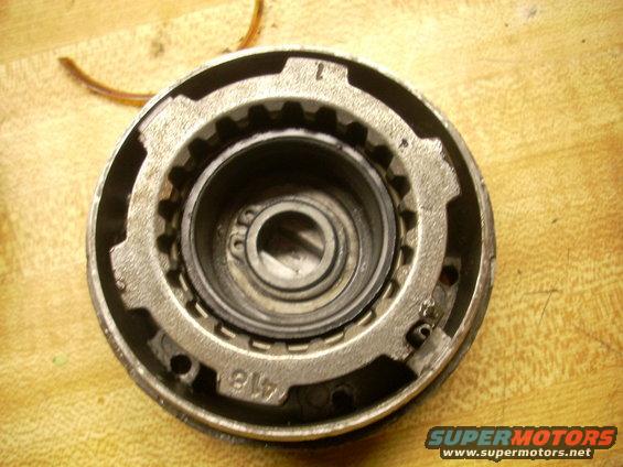 Close-up of a metal automotive part with gear teeth and a bearing. Text '416' is visible