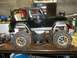 1994 Ford Escort - A black remote control monster truck with large, off-road tires sits on a workbench, surrounded by tools and other items.