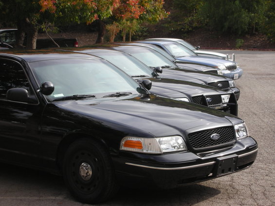 Several black Ford Crown Victoria police cars lined up, front ends visible
