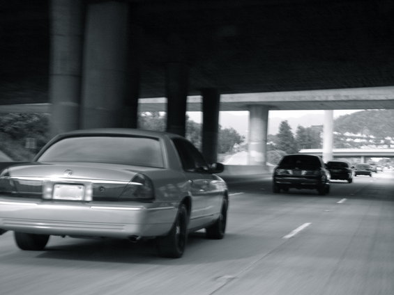 Silver 2004 Ford Crown Victoria from rear, driving on highway under overpass