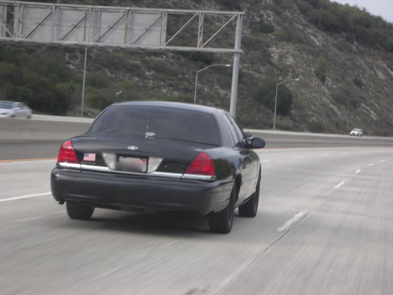 Rear view of a black 2004 Ford Crown Victoria driving on a highway