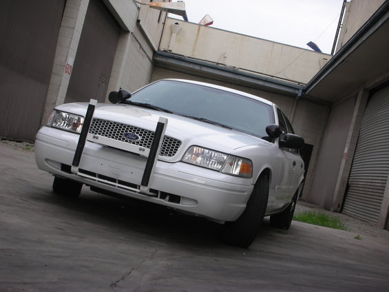 Front view of a white 2004 Ford Crown Victoria Police Interceptor with a push bar in a garage