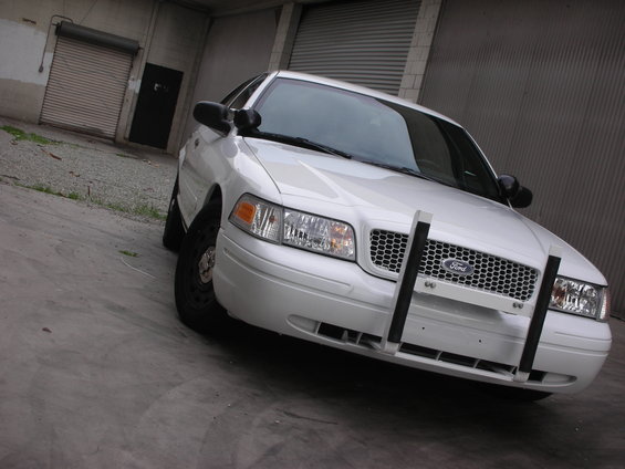 White Ford Crown Victoria with a push bar parked in front of a garage door
