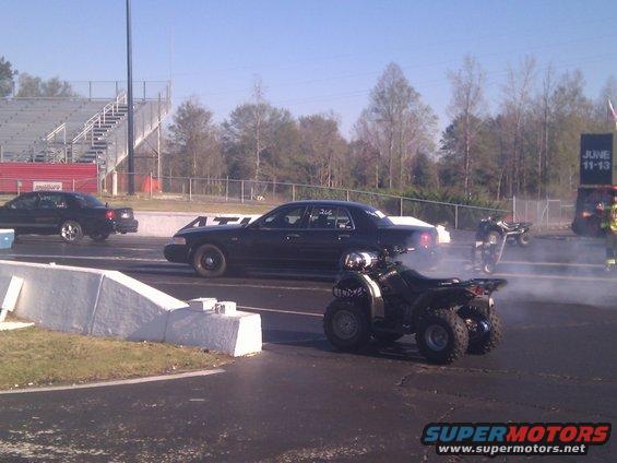 Black 2001 Ford Crown Victoria sedan at drag strip with ATVs