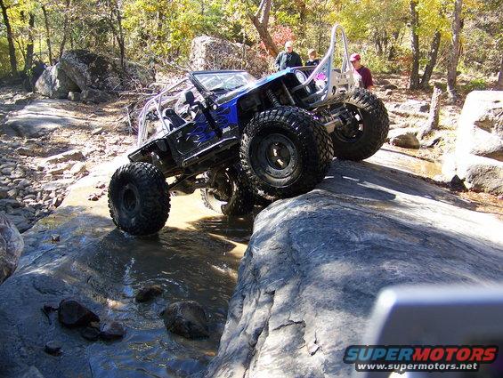 Blue off-road jeep with flames navigating rocky terrain