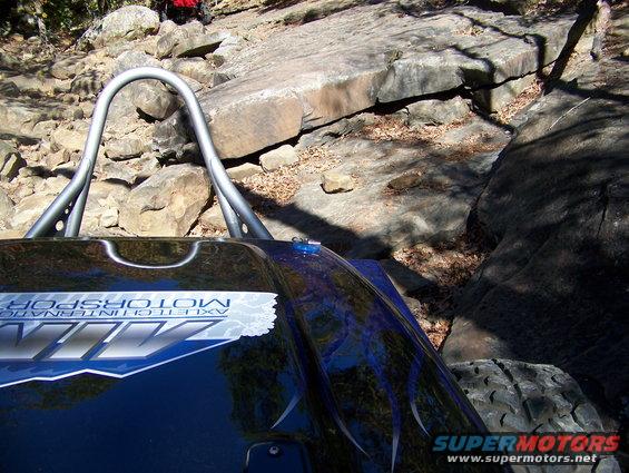 Buggy with roll cage and 'AXLETECHNOLOGY MOTORSPORTS' decal navigating a rocky trail