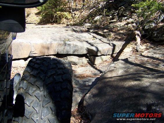 Off-road tire on a vehicle navigating large rocks on a trail