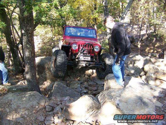 Red Jeep Wrangler navigating a rocky trail