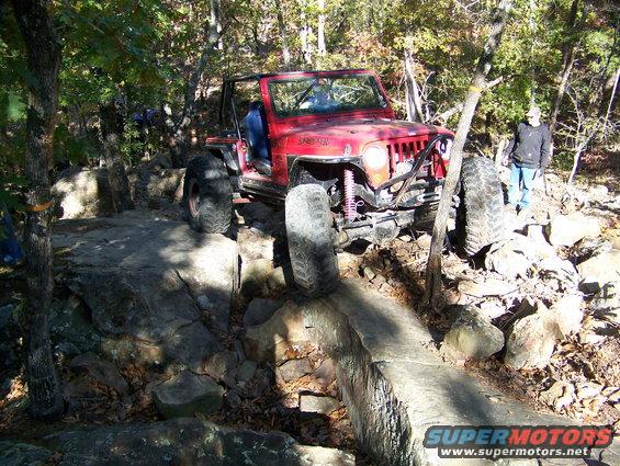 Red Jeep Wrangler navigating rocky terrain