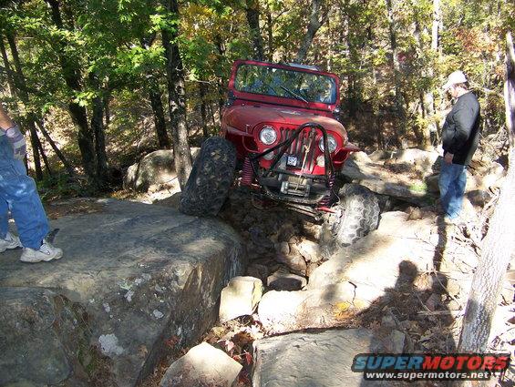 Red Jeep Wrangler navigating rocky terrain
