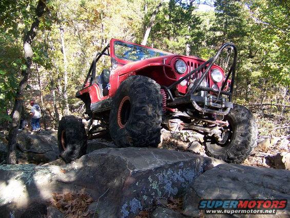 Red off-road jeep with large tires on rocks