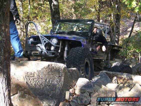 Blue off-road jeep with large tires navigating rocky terrain
