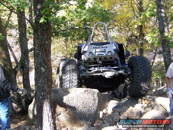 Off-road buggy with large tires navigating rocks, 'AXLE TECH' visible on front