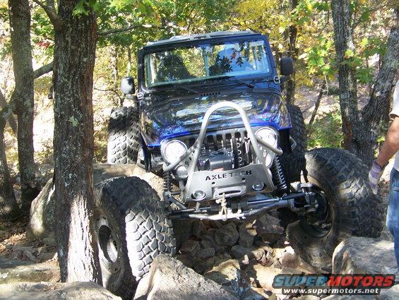Modified Jeep Wrangler with large tires navigating rocky terrain