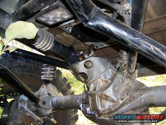 Close-up of off-road vehicle's undercarriage, showing suspension, driveshaft, and differential