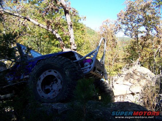 Blue off-road Jeep with custom roll cage on rocky terrain