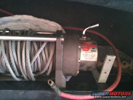 Winch with steel cable and red power cable, mounted on metal bracket