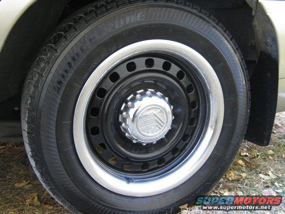 Close-up of a car wheel with a Mercury logo on the hubcap and a Firestone tire