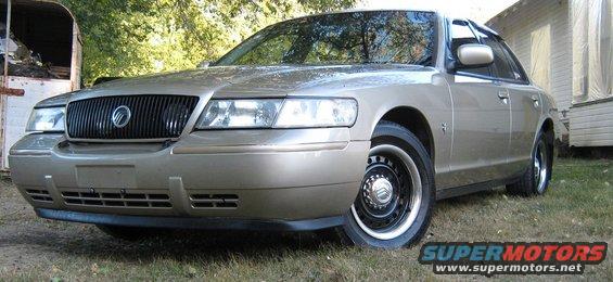 Gold 2000 Mercury Grand Marquis sedan, front 3/4 view, parked on grass
