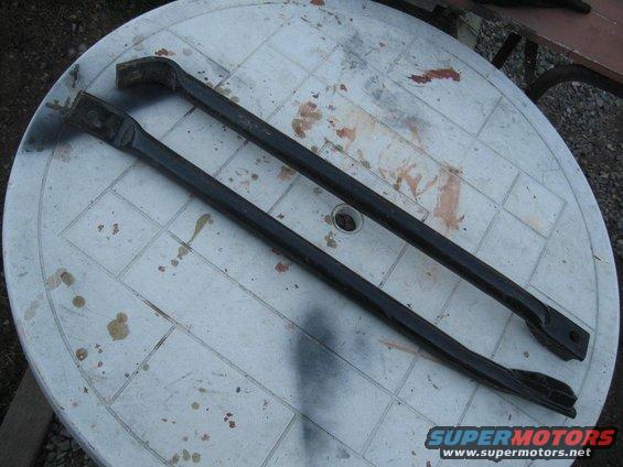 Two black metal bars with angled ends on a white plastic table with stains
