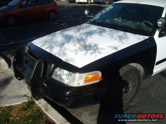 Black and white police car front end with push bumper, parked on curb