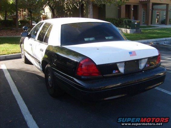 Police car parked in a lot, rear view. White top, black lower half