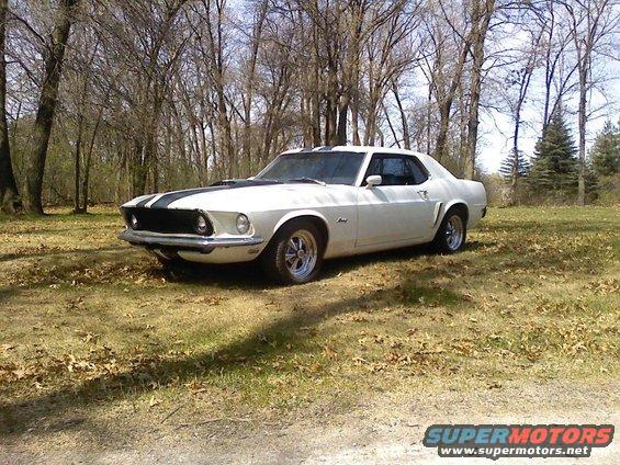 White 1969 Ford Mustang coupe with black racing stripes parked outdoors